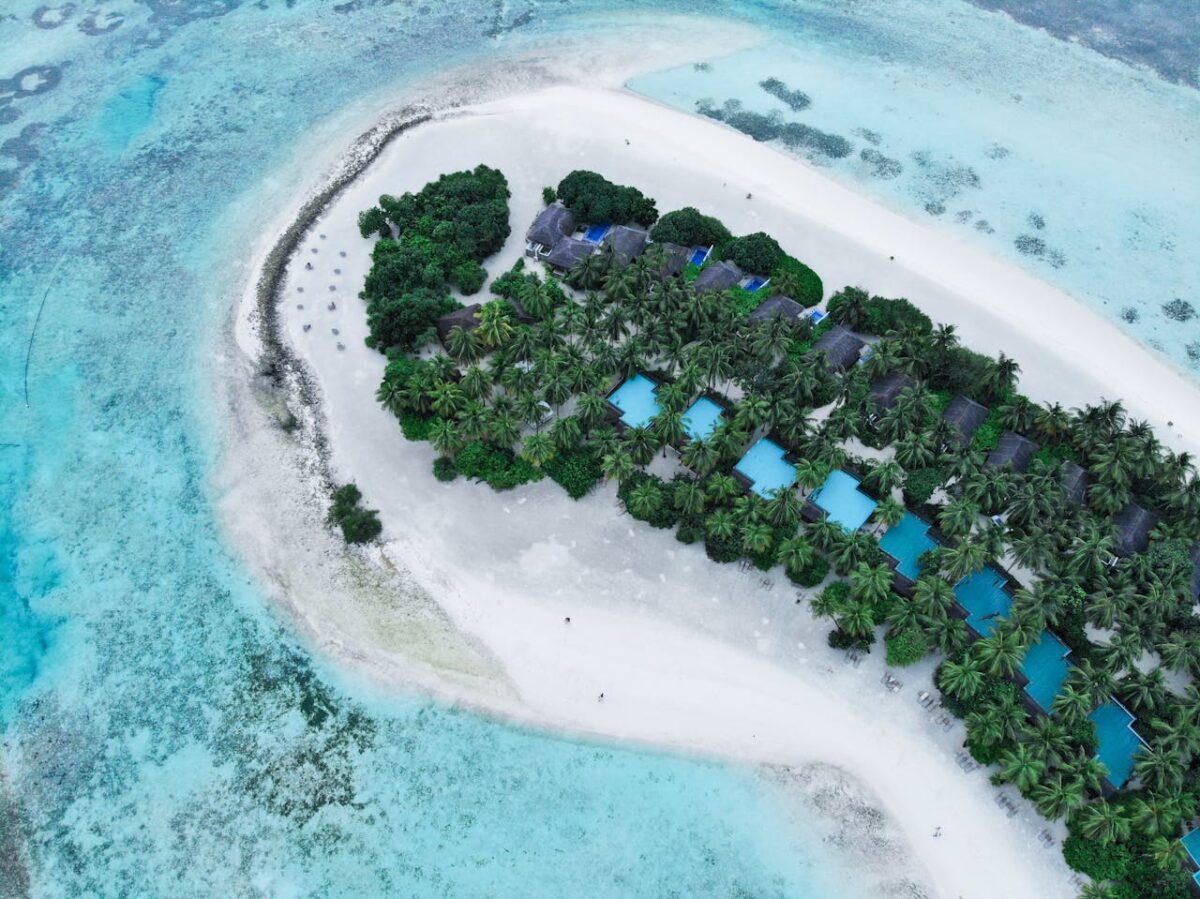 Kel Voyage A stunning aerial view of a tropical island resort with turquoise waters and lush greenery.