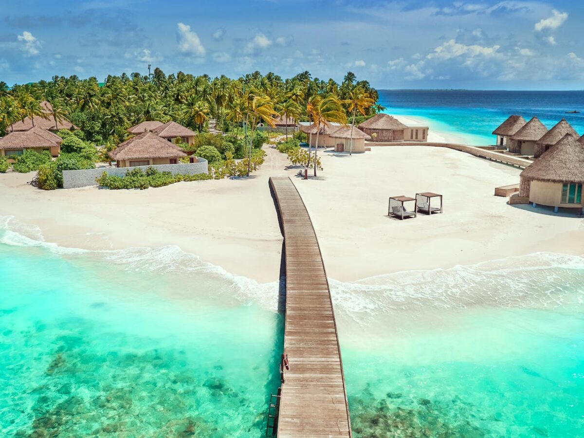 Kel Voyage A breathtaking aerial view of a tropical resort with turquoise water and white sandy beaches.